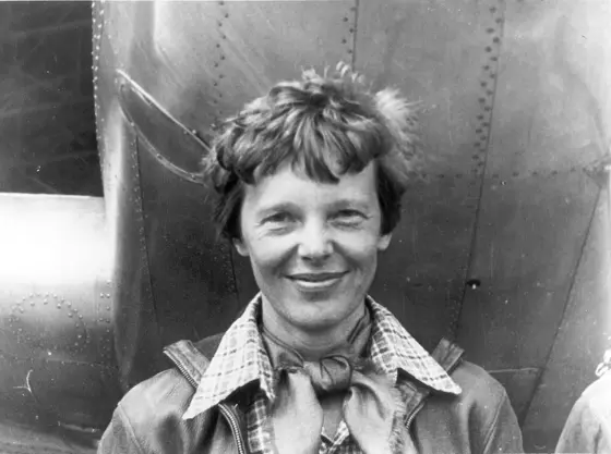 Amelia Earhart standing under the nose of her Lockheed Electra